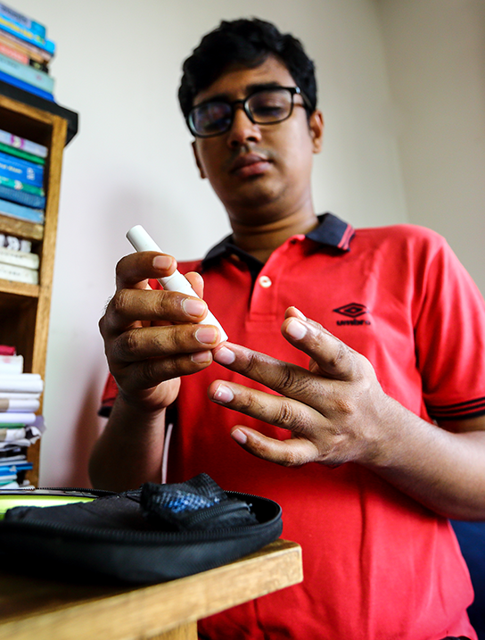 Young man pricking his finger to measure blood glucose